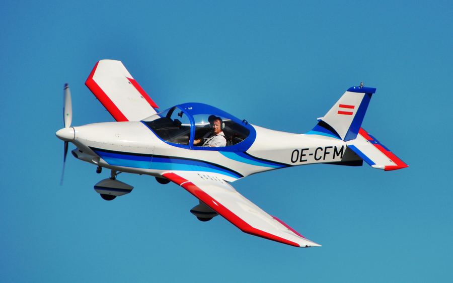 Ultraleichtflugzeug OE-CFM in rot-weiß-blauer Lackierung im Flug vor tiefblauem Himmel